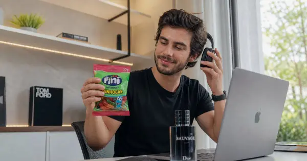 Frasco de perfume Moschino ao lado de um pacote de balas Fini, simbolizando a parceria para o lançamento no Brasil.